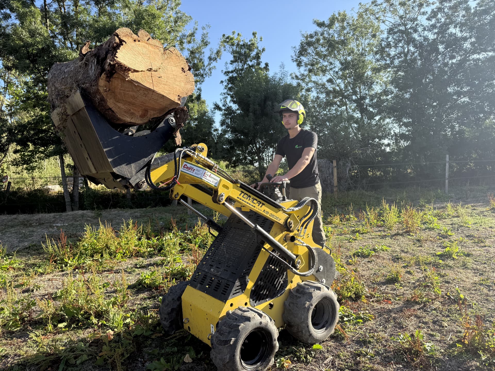 Chargeur compact soulevant une souche d'arbre